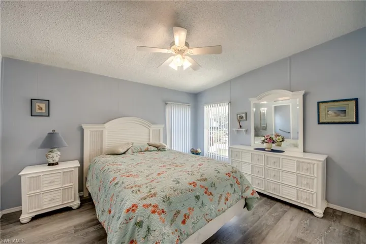 Bedroom with wood finished floors, ceiling fan, a textured ceiling, and vaulted ceiling