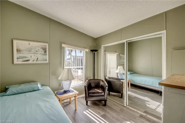 Bedroom featuring a textured ceiling, a closet, a decorative wall, and wood finished floors