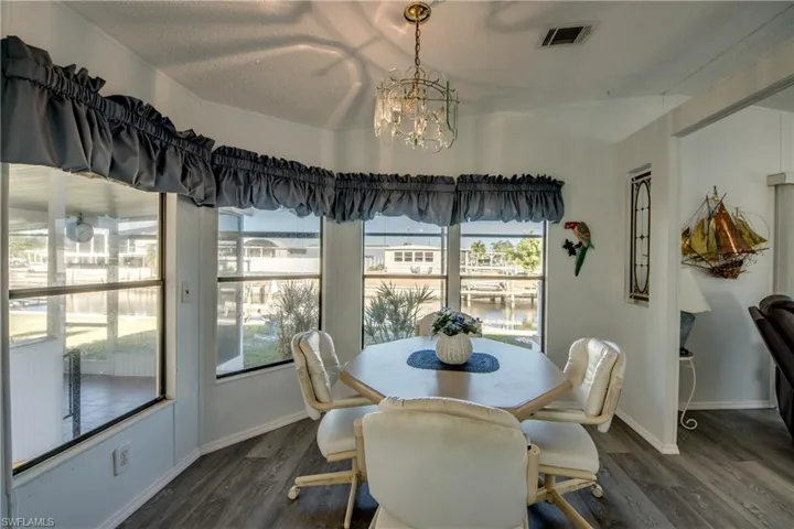 Dining space featuring a chandelier, dark wood finished floors, a water view, and a textured ceiling