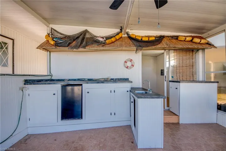 Out door Kitchen with white cabinets, wood ceiling, dark countertops, and fridge