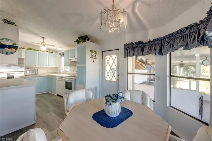 Dining space with ceiling fan, a textured ceiling, wood finished floors, and a chandelier