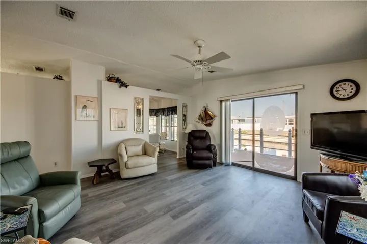 Living area with a textured ceiling, wood finished floors, and ceiling fan