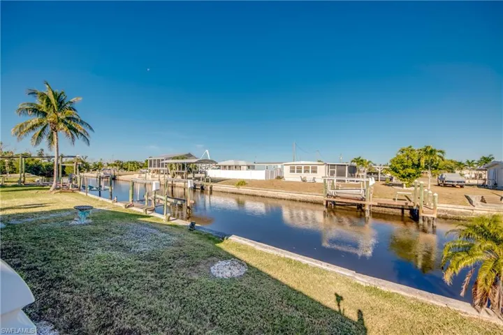 Dock with boat lift, a water view, and a yard