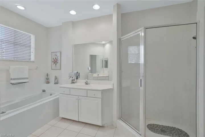 Bathroom featuring a shower stall, light tile patterned floors, a bath, vanity, and recessed lighting