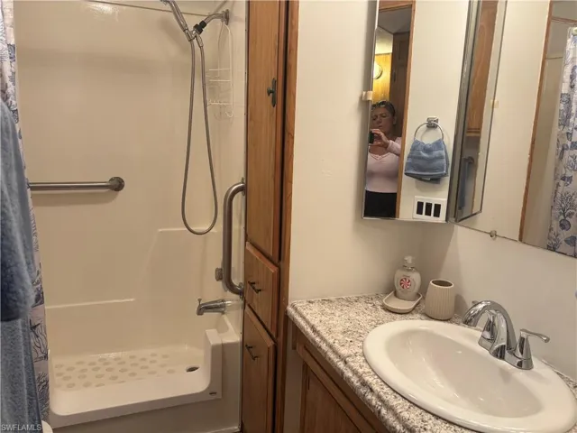 Bathroom with a shower with curtain and vanity