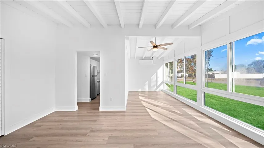 Unfurnished living room featuring lofted ceiling with beams, ceiling fan, light wood finished floors, and wooden ceiling