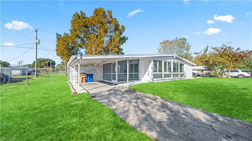 View of front facade with an attached carport, driveway, and a sunroom