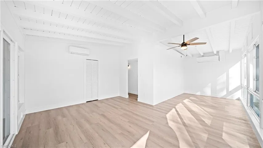 Unfurnished living room with light wood-type flooring, a ceiling fan, and lofted ceiling with beams