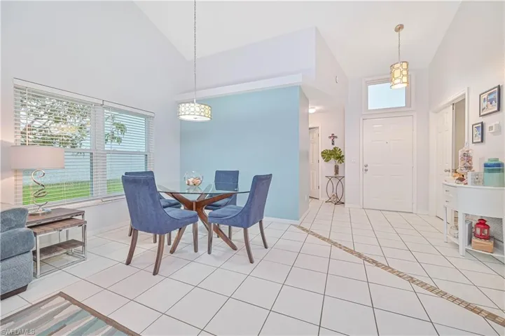 Dining space with lofted ceiling, plenty of natural light, and light tile patterned flooring