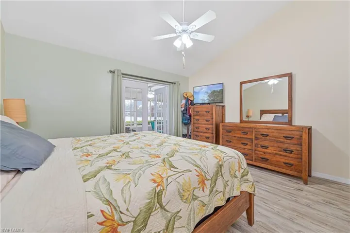 Bedroom with light wood finished floors, lofted ceiling, access to outside, and a ceiling fan