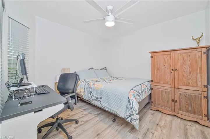 Bedroom featuring an office area, light wood-style floors, and ceiling fan
