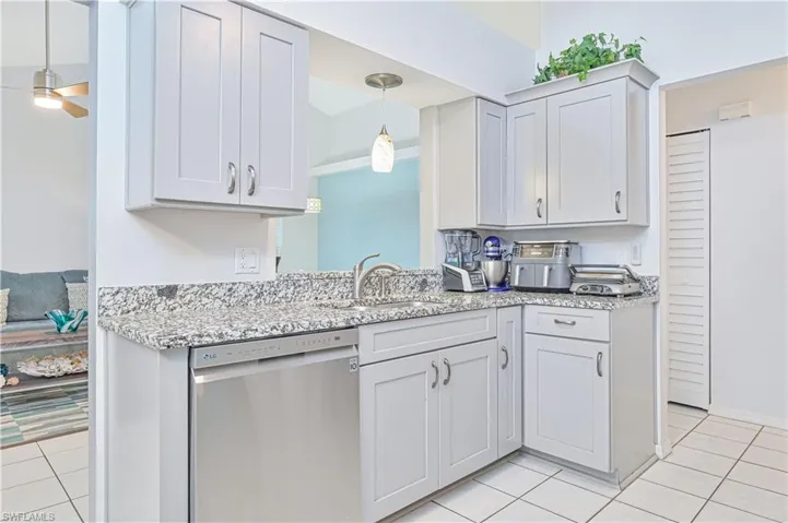 Kitchen featuring stainless steel dishwasher, a ceiling fan, light stone countertops, and light tile patterned flooring