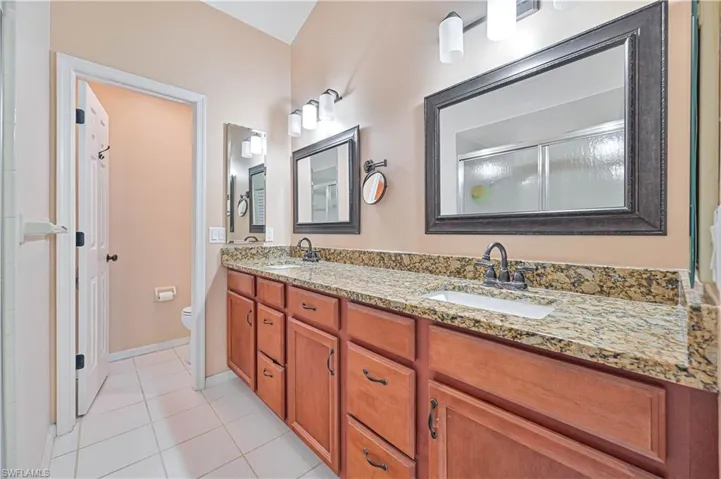 Bathroom featuring double vanity, light tile patterned flooring, and a shower with shower door