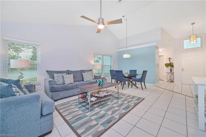 Living area with light tile patterned floors, vaulted ceiling, and a ceiling fan