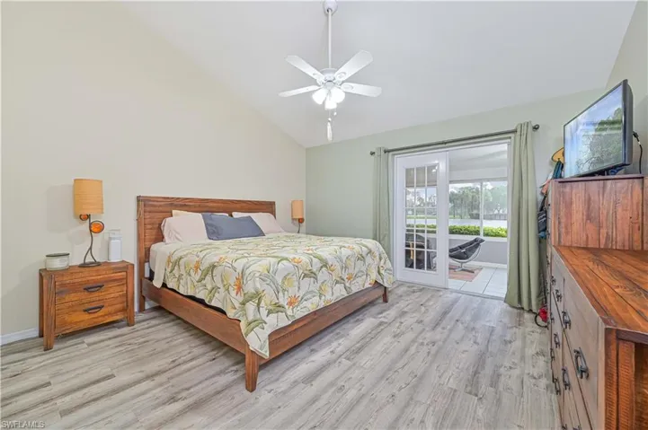 Bedroom featuring access to exterior, lofted ceiling, light wood-type flooring, and ceiling fan