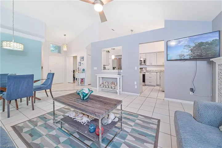 Living area featuring lofted ceiling, ceiling fan, and light tile patterned floors