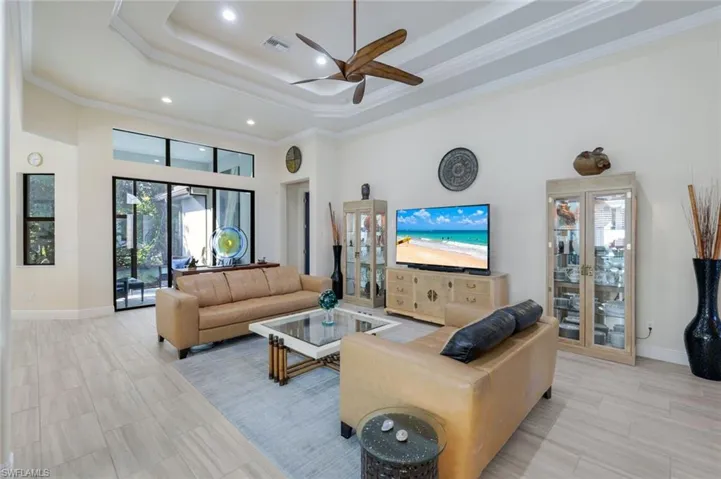 Living room with crown molding, ceiling fan, a tray ceiling, and a high ceiling
