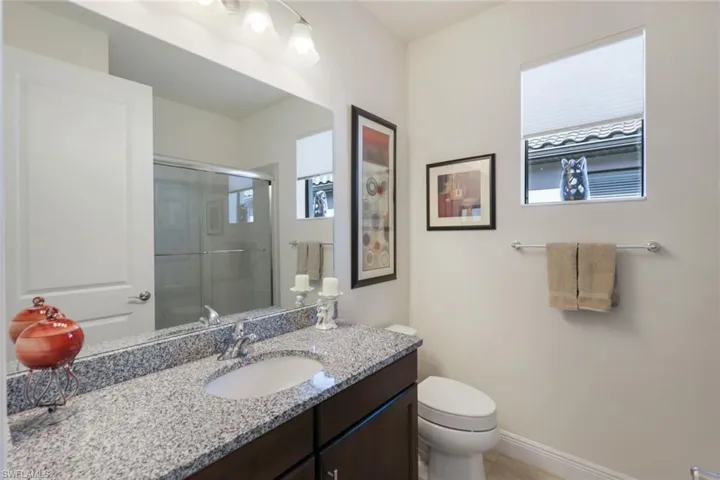 Bathroom featuring walk in shower, vanity, and toilet