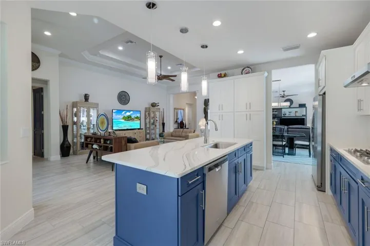 Kitchen with blue cabinetry, sink, white cabinetry, a center island with sink, and appliances with stainless steel finishes