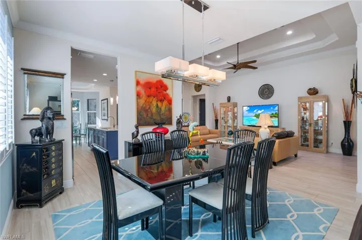 Dining space featuring sink, ceiling fan, light hardwood / wood-style floors, a raised ceiling, and crown molding