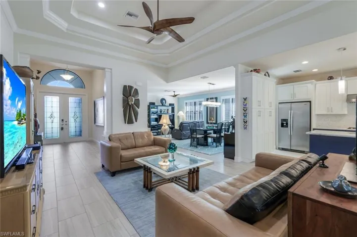 Living room with a tray ceiling, ornamental molding, french doors, and ceiling fan
