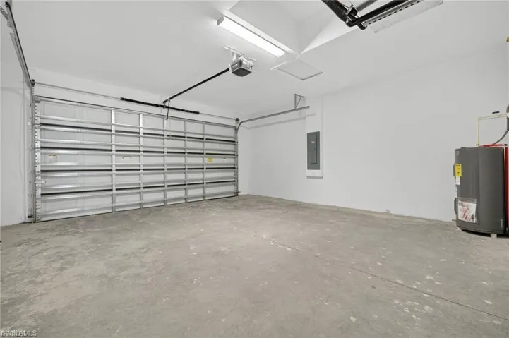 Garage featuring water heater, a garage door opener, and electric panel