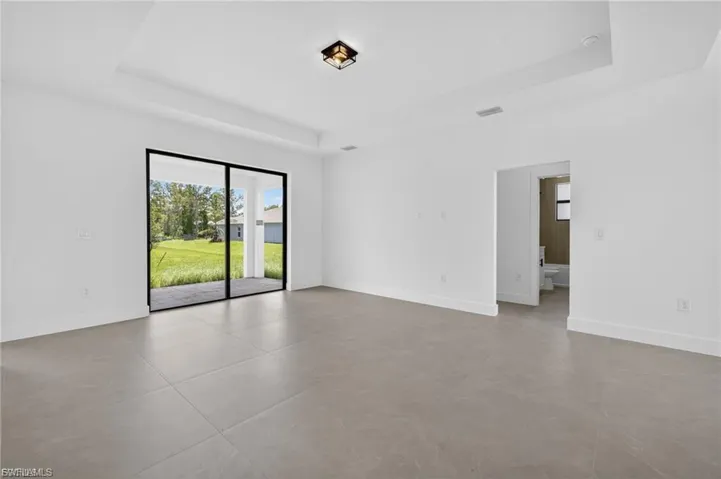 Empty room with a tray ceiling and concrete flooring