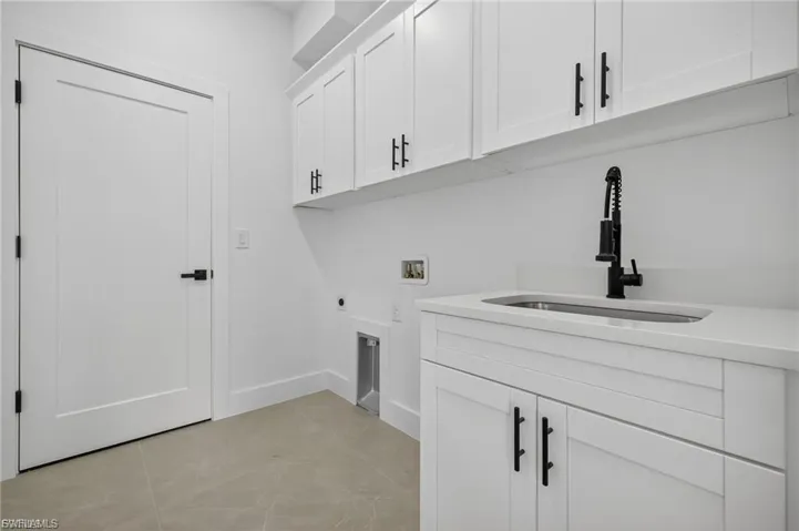 Laundry area featuring hookup for a washing machine, cabinet space, hookup for an electric dryer, and light tile patterned floors