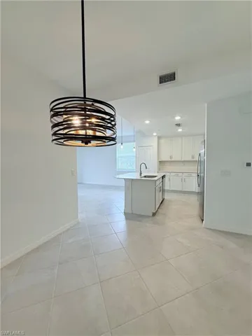 Unfurnished dining area with a chandelier, light tile patterned floors, and recessed lighting