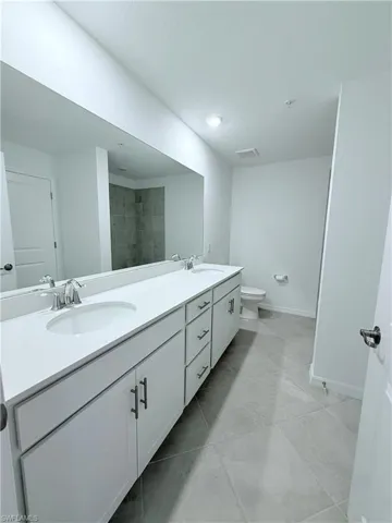 Bathroom featuring double vanity and a tile shower