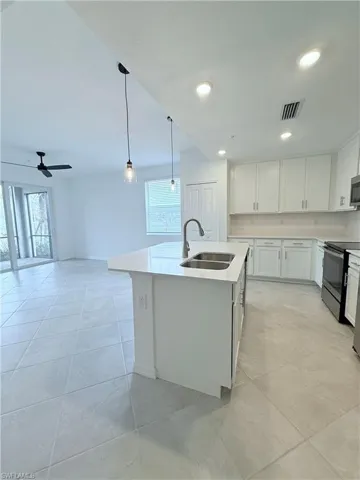 Kitchen with white cabinetry, a kitchen island with sink, pendant lighting, stainless steel appliances, and ceiling fan