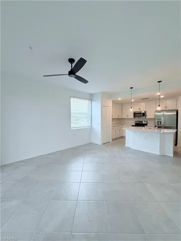 Unfurnished living room featuring a ceiling fan, light tile patterned floors, and recessed lighting