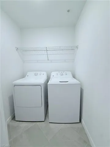 Laundry room with washer and dryer and light tile patterned floors