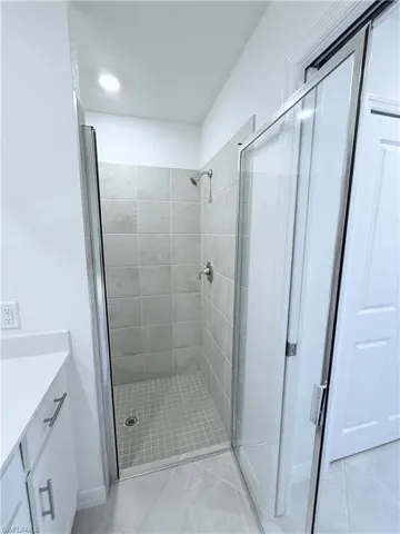 Full bathroom with a shower stall, vanity, and light tile patterned floors