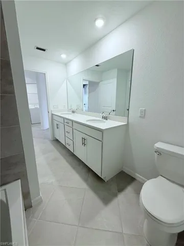 Bathroom with double vanity and a textured wall