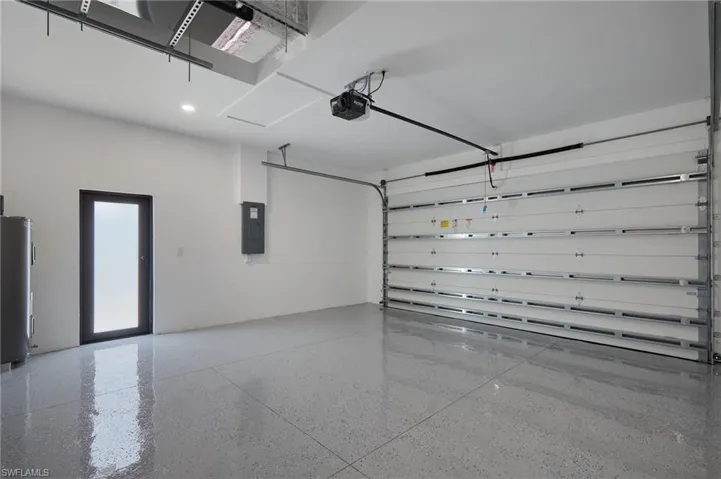 Garage with a garage door opener, water heater, and electric panel