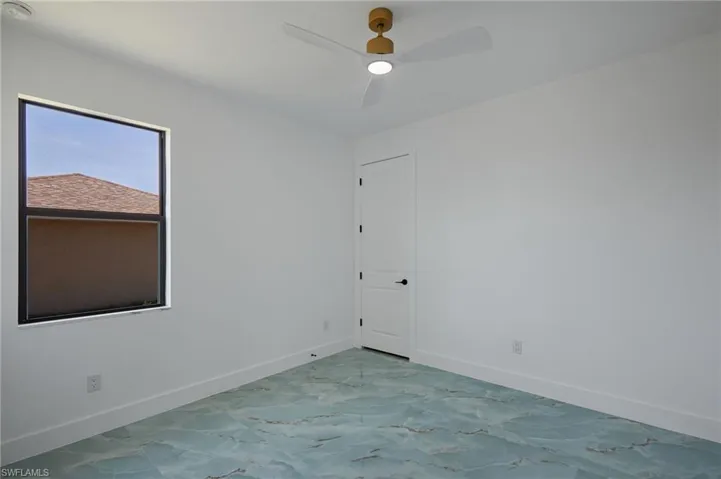 Spare room featuring a ceiling fan, marble finish floor, and baseboards