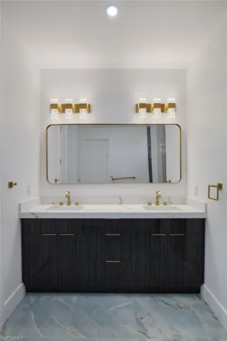 Bathroom with marble finish floor, a sink, and baseboards