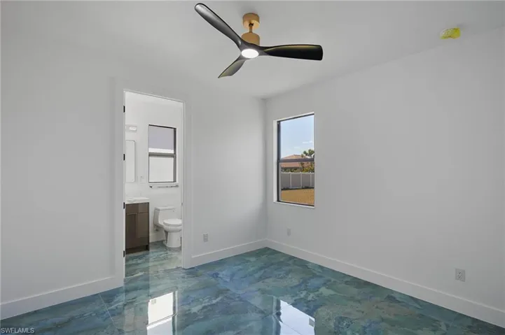 Unfurnished bedroom with connected bathroom, a ceiling fan, marble finish floor, and baseboards