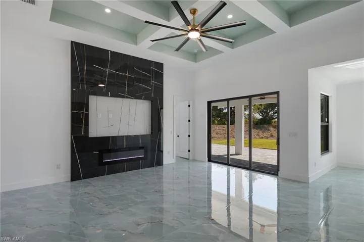 Unfurnished living room with baseboards, coffered ceiling, marble finish floor, and a high ceiling