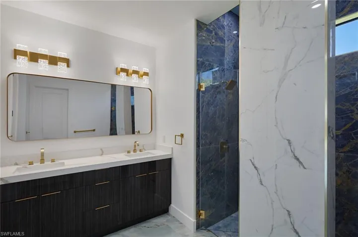 Full bathroom with double vanity, a sink, marble finish floor, and a marble finish shower