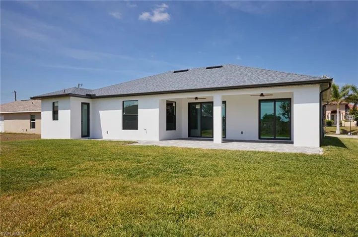 Rear view of house with a patio, a shingled roof, stucco siding, ceiling fan, and a lawn