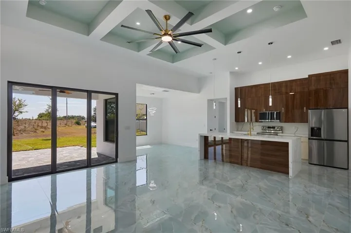 Kitchen featuring modern cabinets, coffered ceiling, light countertops, a towering ceiling, and appliances with stainless steel finishes