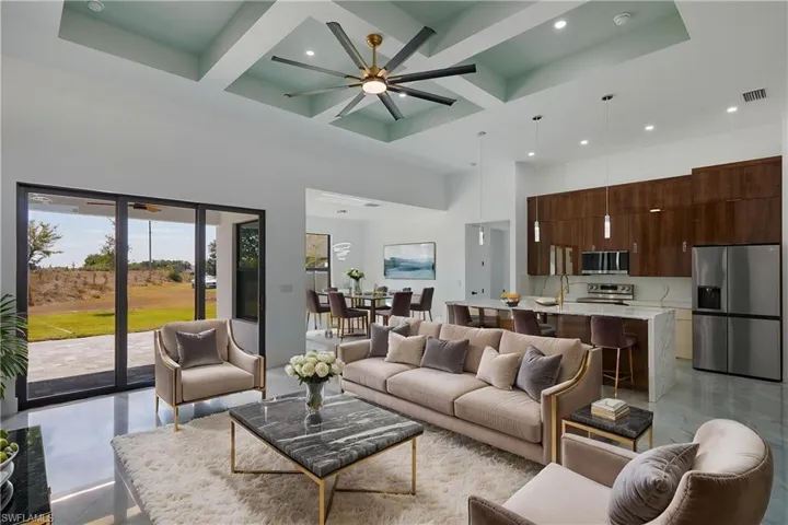 Living room featuring a high ceiling, recessed lighting, coffered ceiling, ceiling fan, and beamed ceiling