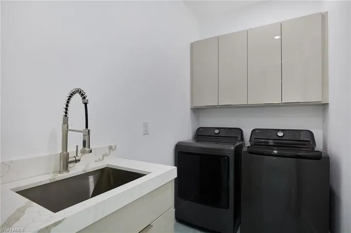 Washroom featuring independent washer and dryer, cabinet space, and a sink