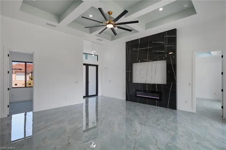 Unfurnished living room with visible vents, ceiling fan, coffered ceiling, and baseboards