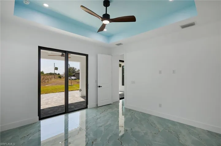 Bed room with a raised ceiling, a ceiling fan, visible vents, and baseboards