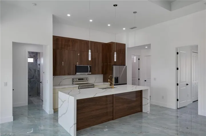 Kitchen with a sink, modern cabinets, stainless steel appliances, a large island, and marble finish floor