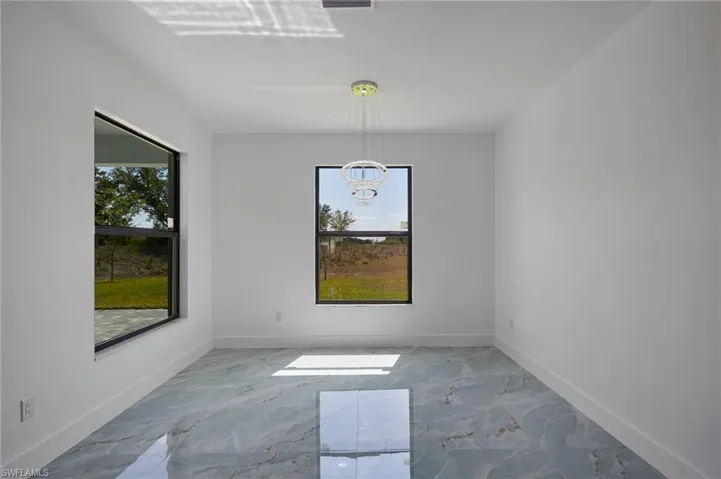 Unfurnished dining area featuring a notable chandelier, marble finish floor, and baseboards