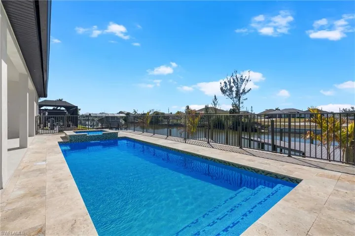 Integrated pool / hot tub with a patio area, a fenced backyard, a water view, and a residential view